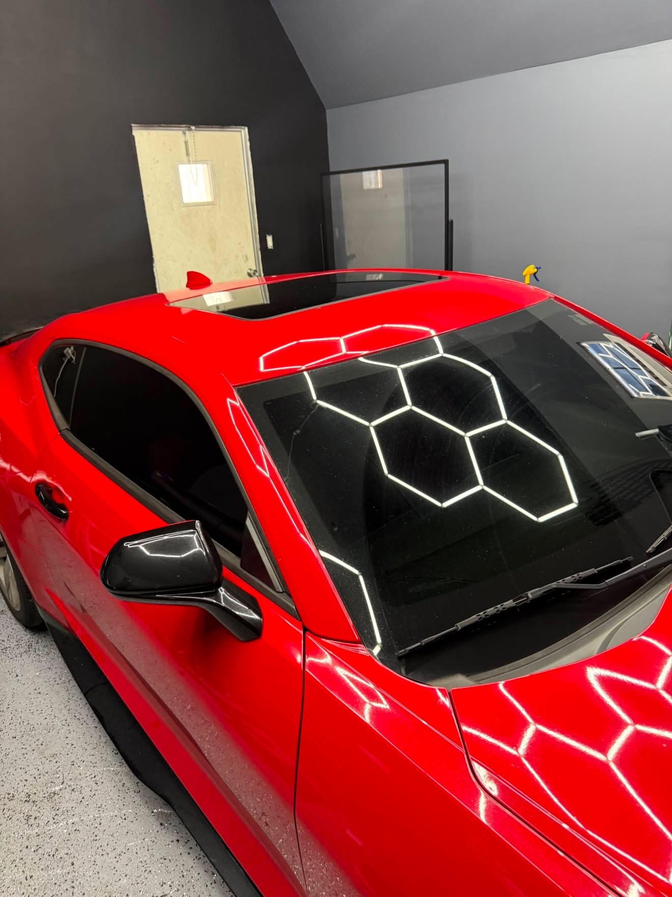 Red sports coupe with ceramic tint under hexagon lights